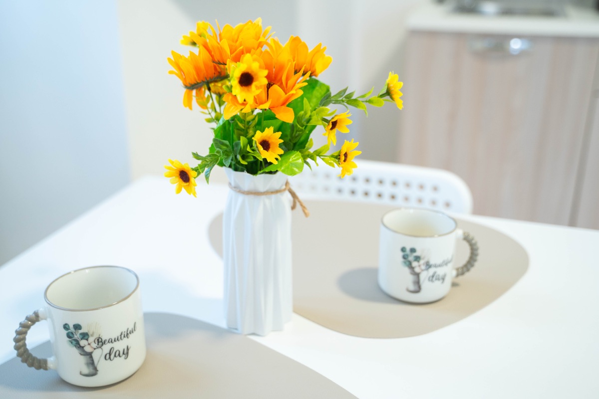 Tavolino con vaso di girasoli e due tazze