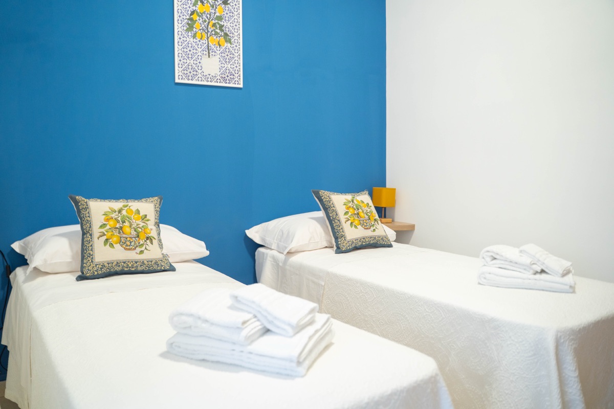 Letti singoli con parete blu e cuscini decorati con limoni