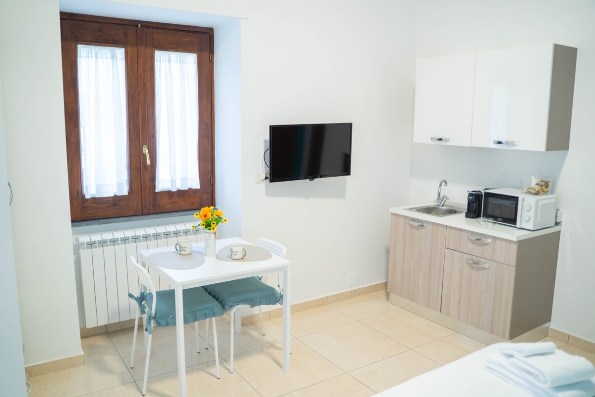 Angolo cottura con microonde e macchina del caffè, tavolino per due e TV a parete
