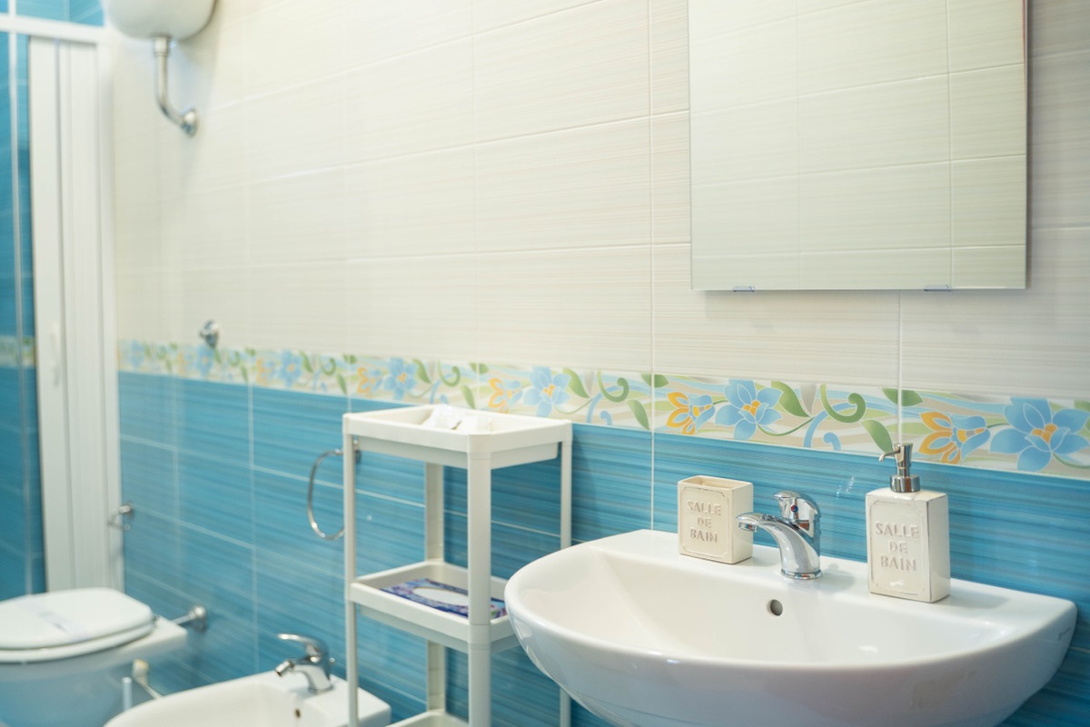 Bagno privato con lavabo e piastrelle azzurre decorate a fiori